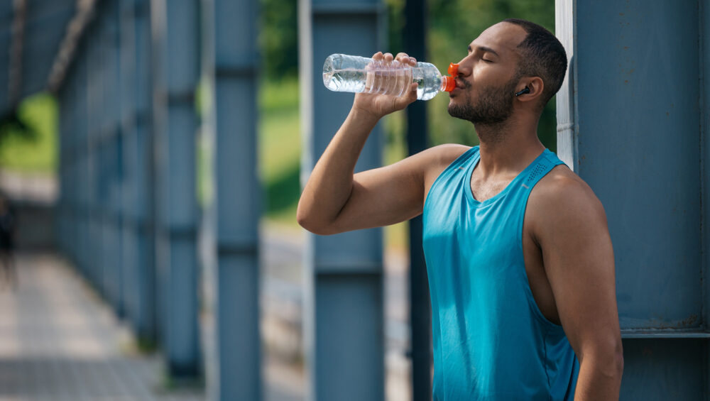 A Guy in A Bright Blue Tank Top Drinking Water