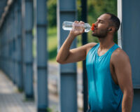 A Guy in A Bright Blue Tank Top Drinking Water