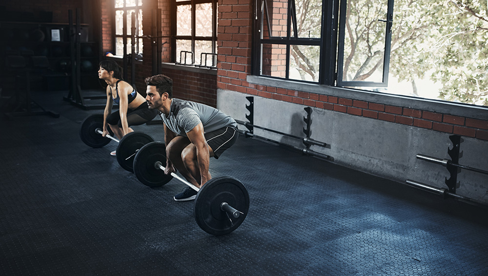 Male & Female at the gym doing deadlifts.